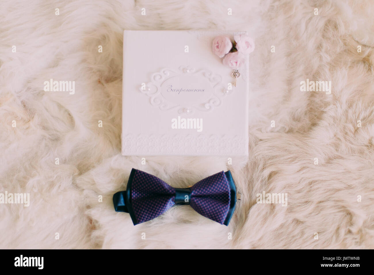Blue bow tie and wedding invitation card isolated on white fur background. Stock Photo