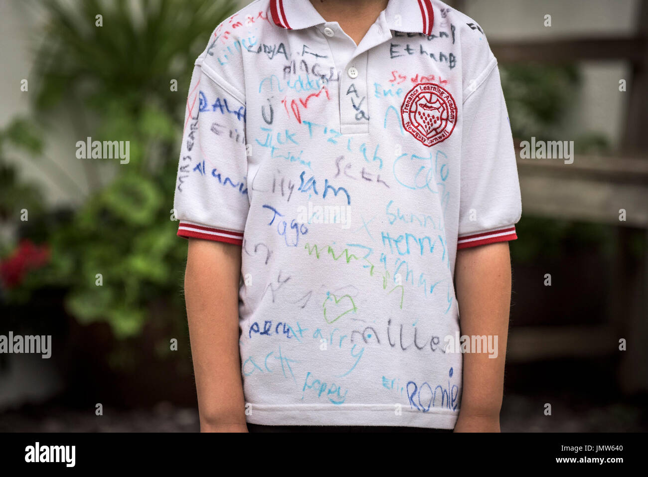 A young Junior school pupil wearing a white shirt signed by all his friends at the end of the school summer term. Newquay, Cornwall. Stock Photo