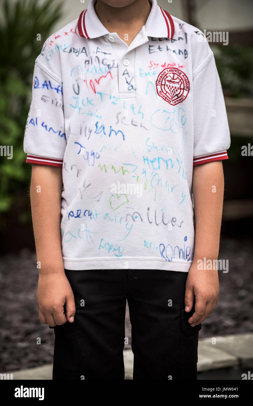 A young Junior school pupil wearing a white shirt signed by all his friends at the end of the school summer term. Newquay, Cornwall. Stock Photo