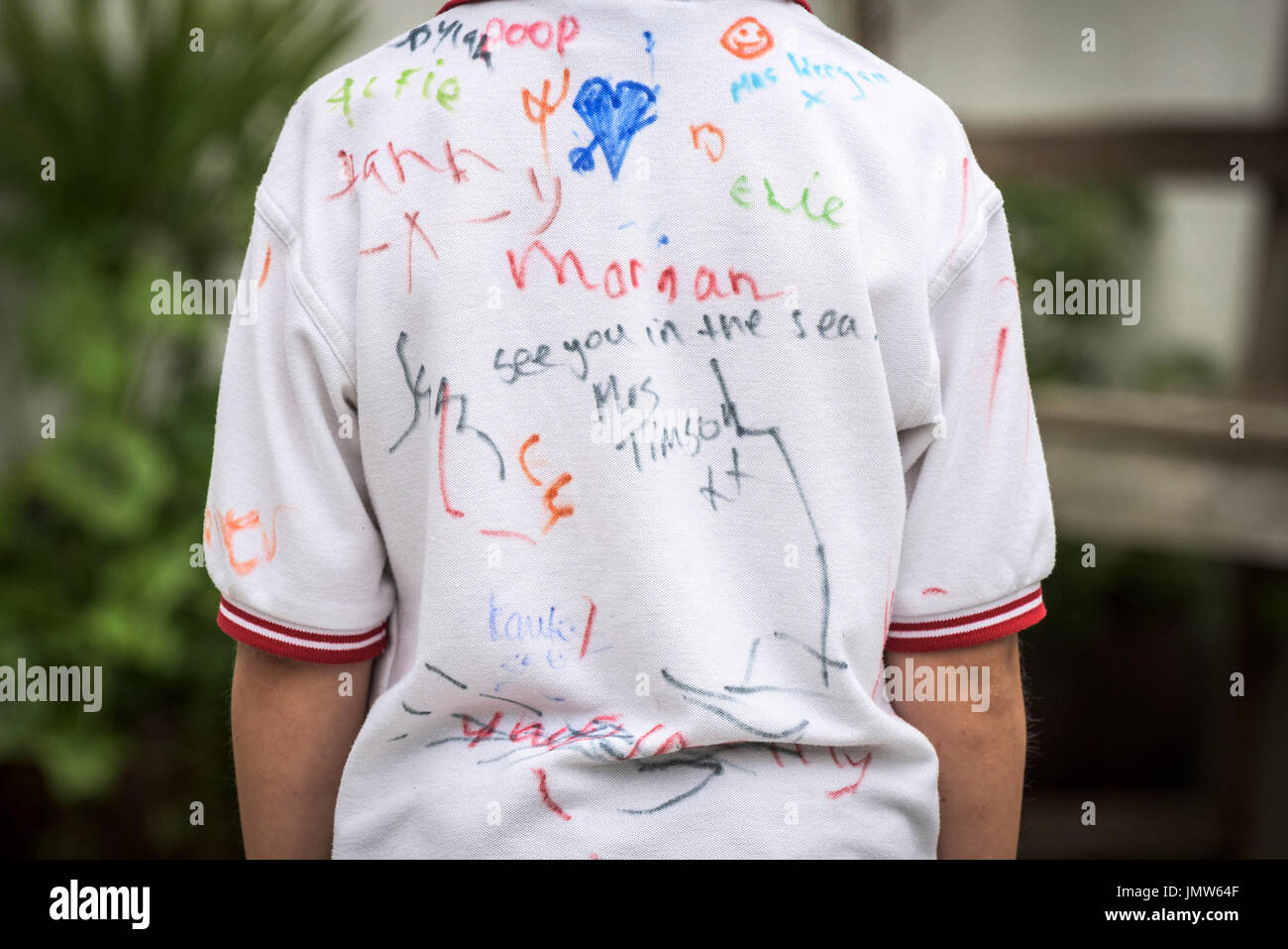 A young Junior school pupil wearing a white shirt signed by all his friends at the end of the school summer term. Newquay, Cornwall. Stock Photo