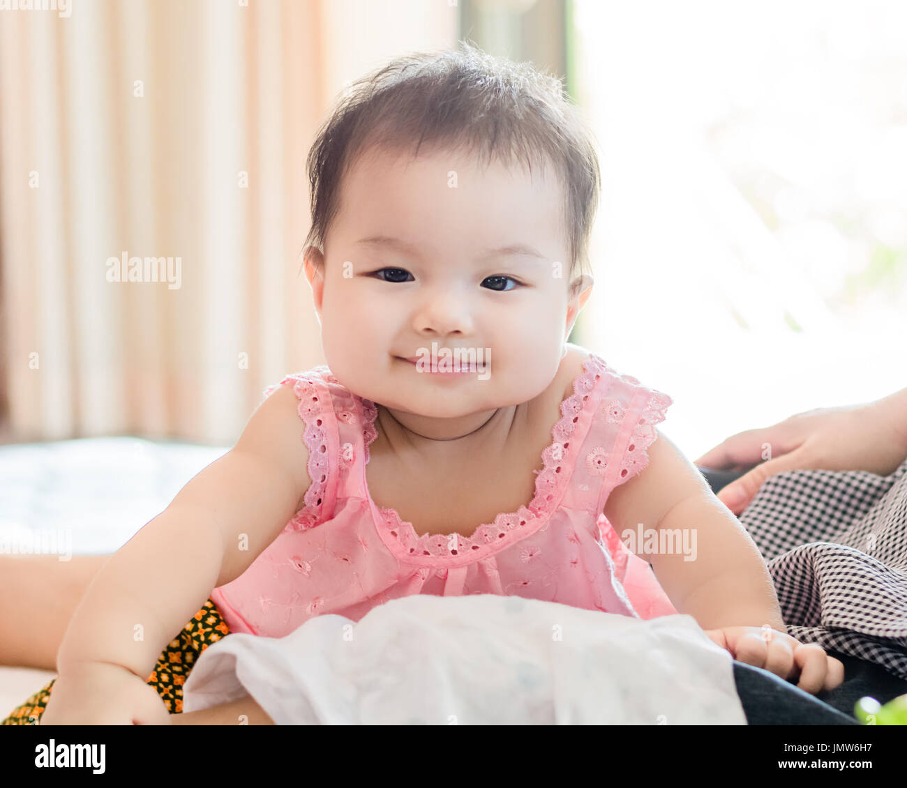 Portrait of a little adorable infant baby girl sitting on the bed and smile Stock Photo