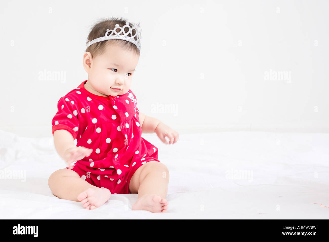 Portrait of a little adorable infant baby girl sitting on the bed with ...