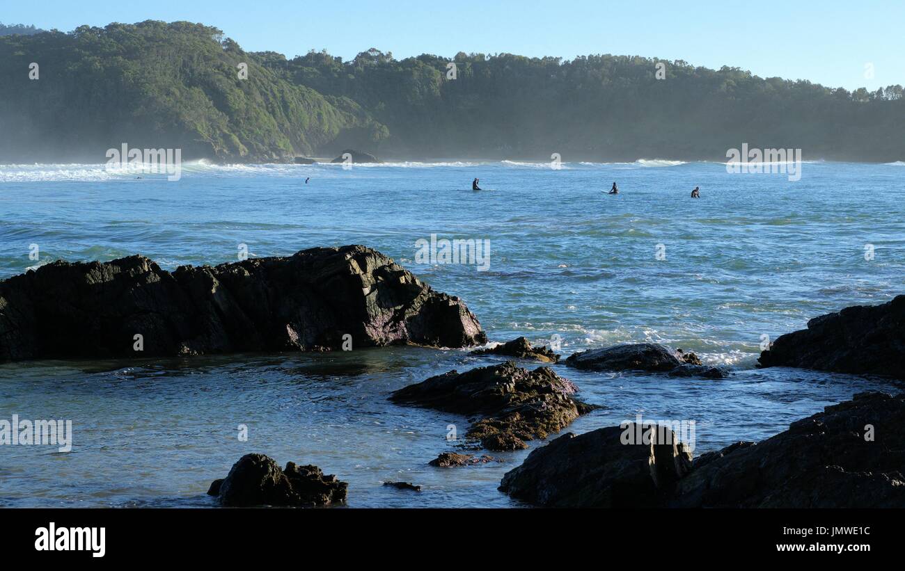 Sea view, rocks swimmers or surfers, sea waves and hills in Australia Stock Photo