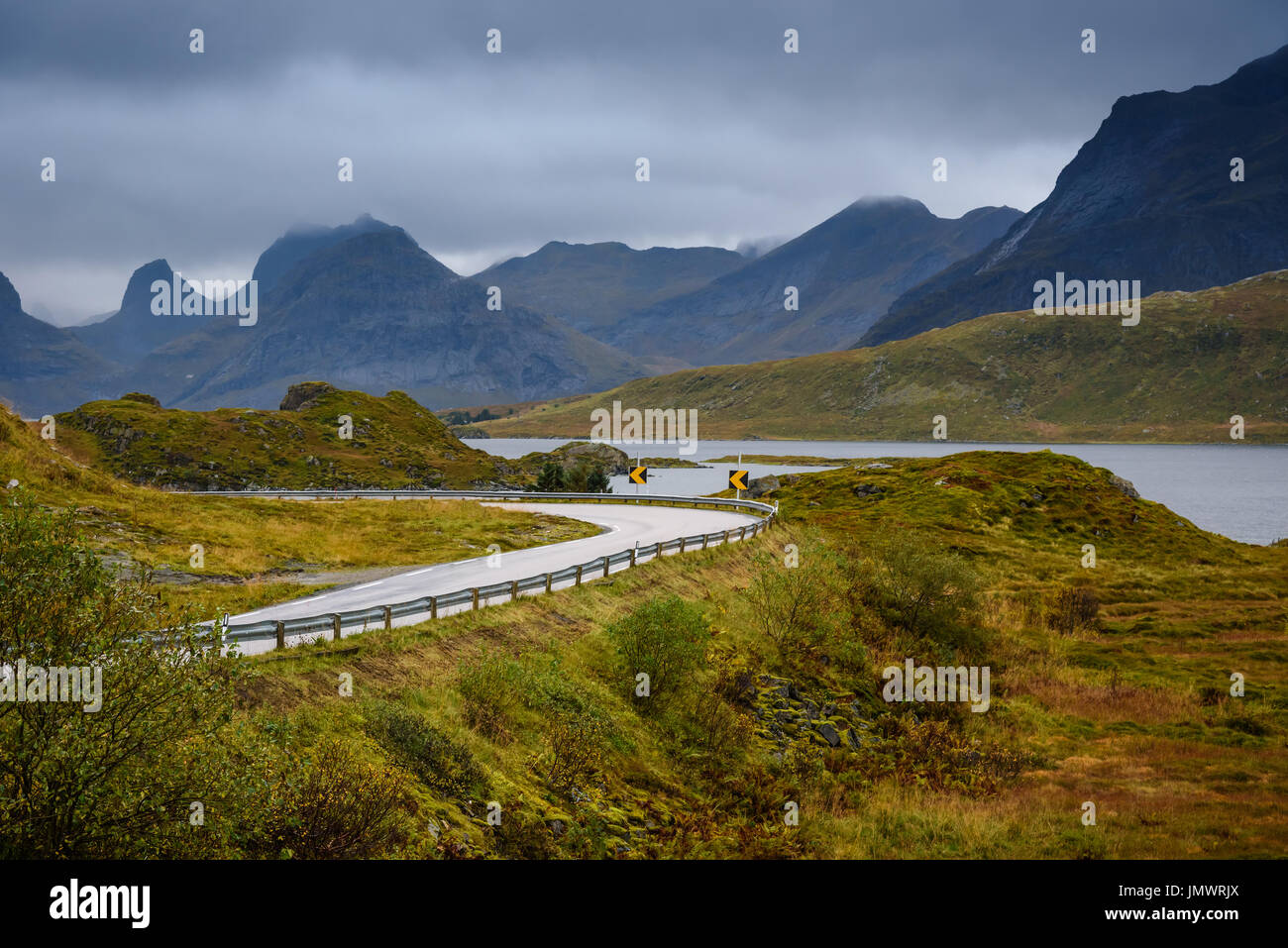 Asphalt sharp curved road along the forest and mountain, Lofoten, Norway Stock Photo