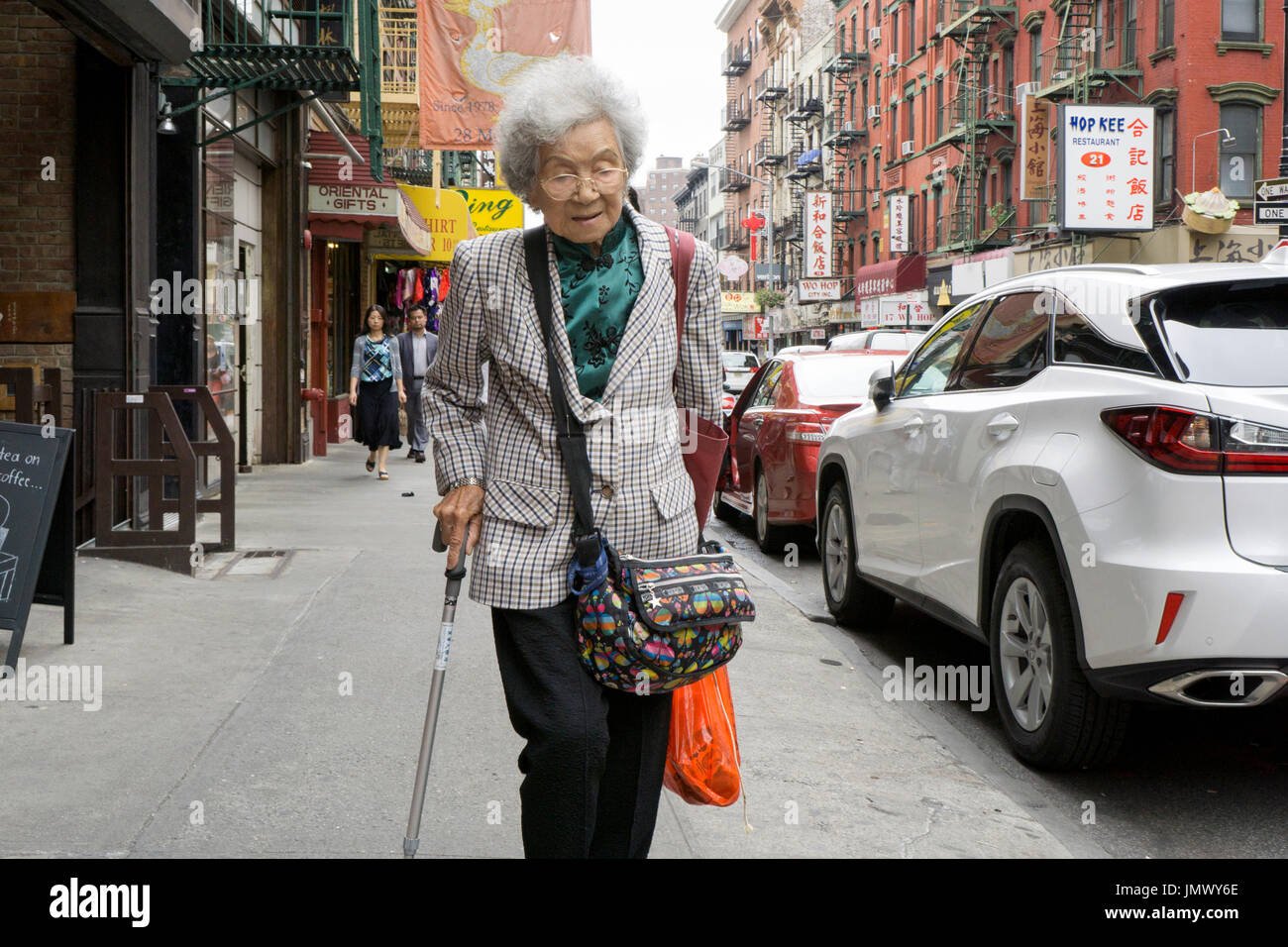 An older Chinese American woman outside shopping on a summer day on Mott Street in Chinatown, Lower Manhattan, New York City Stock Photo