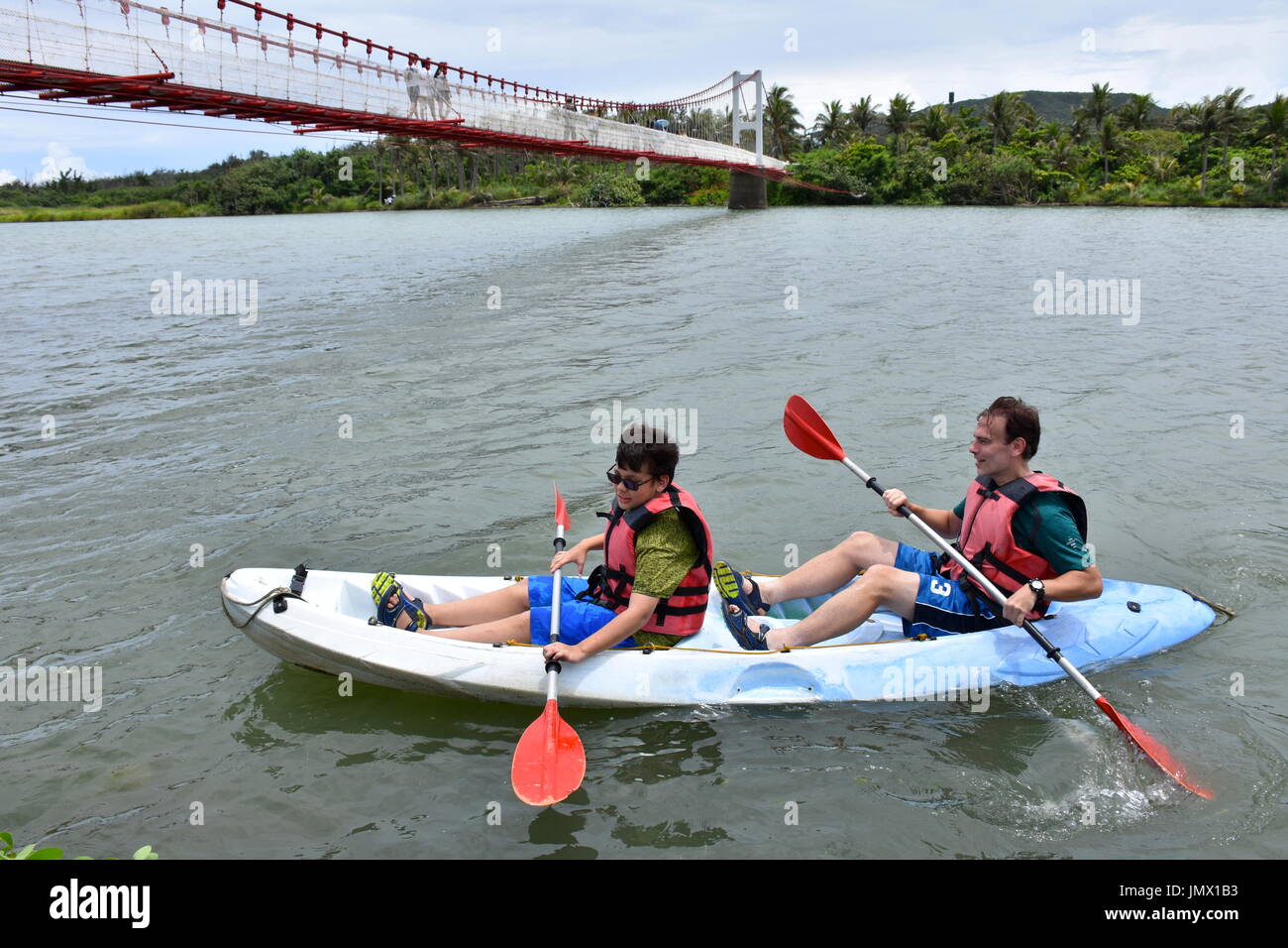 My husband and son canoeing on a lake outlet near coming from the ocean in Kenting, Taiwan. So fun, but a hot summer day. Stock Photo