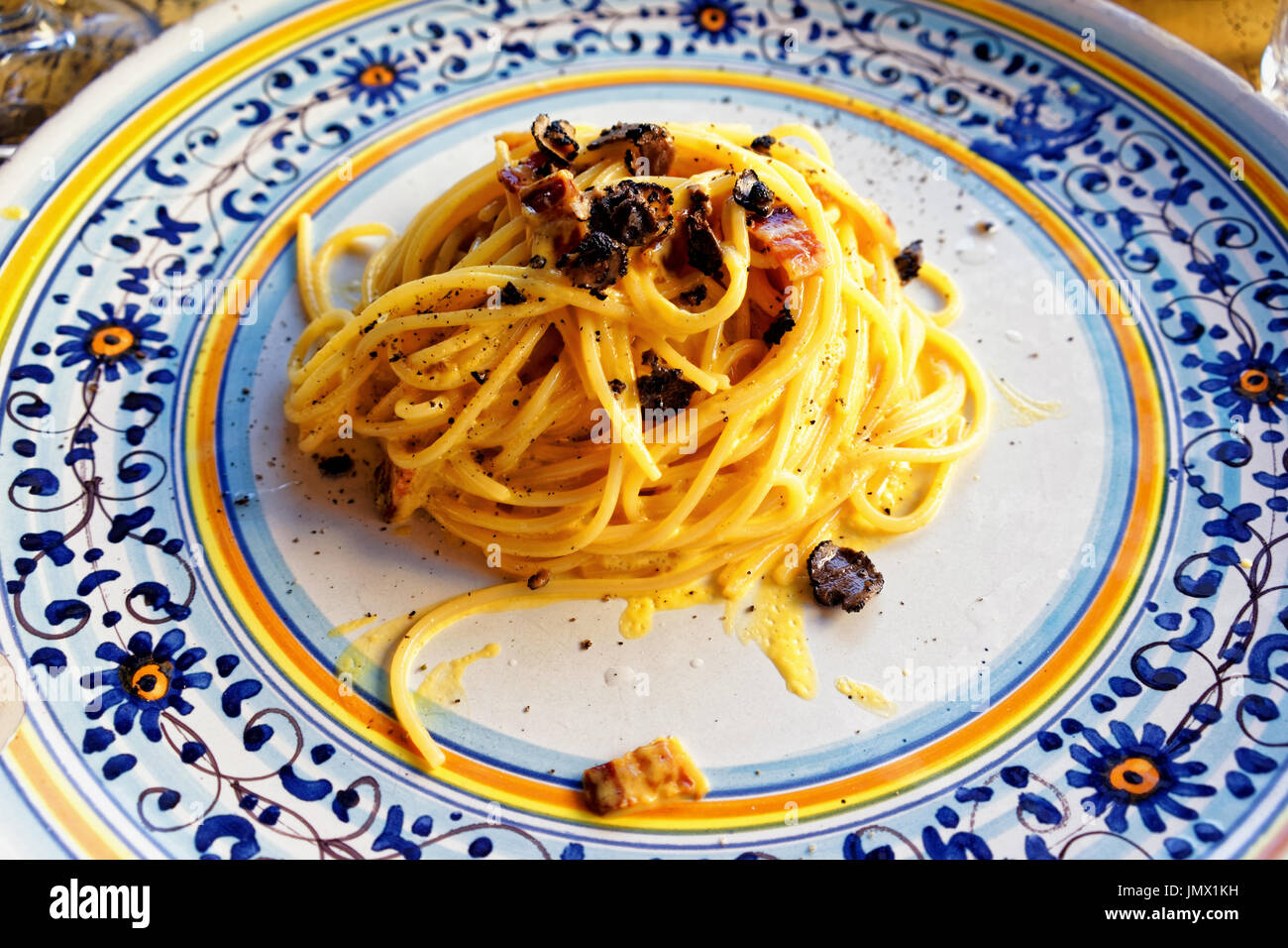 Italian traditional pasta alla carbonara with truffles mushrooms in plate at restaurant in