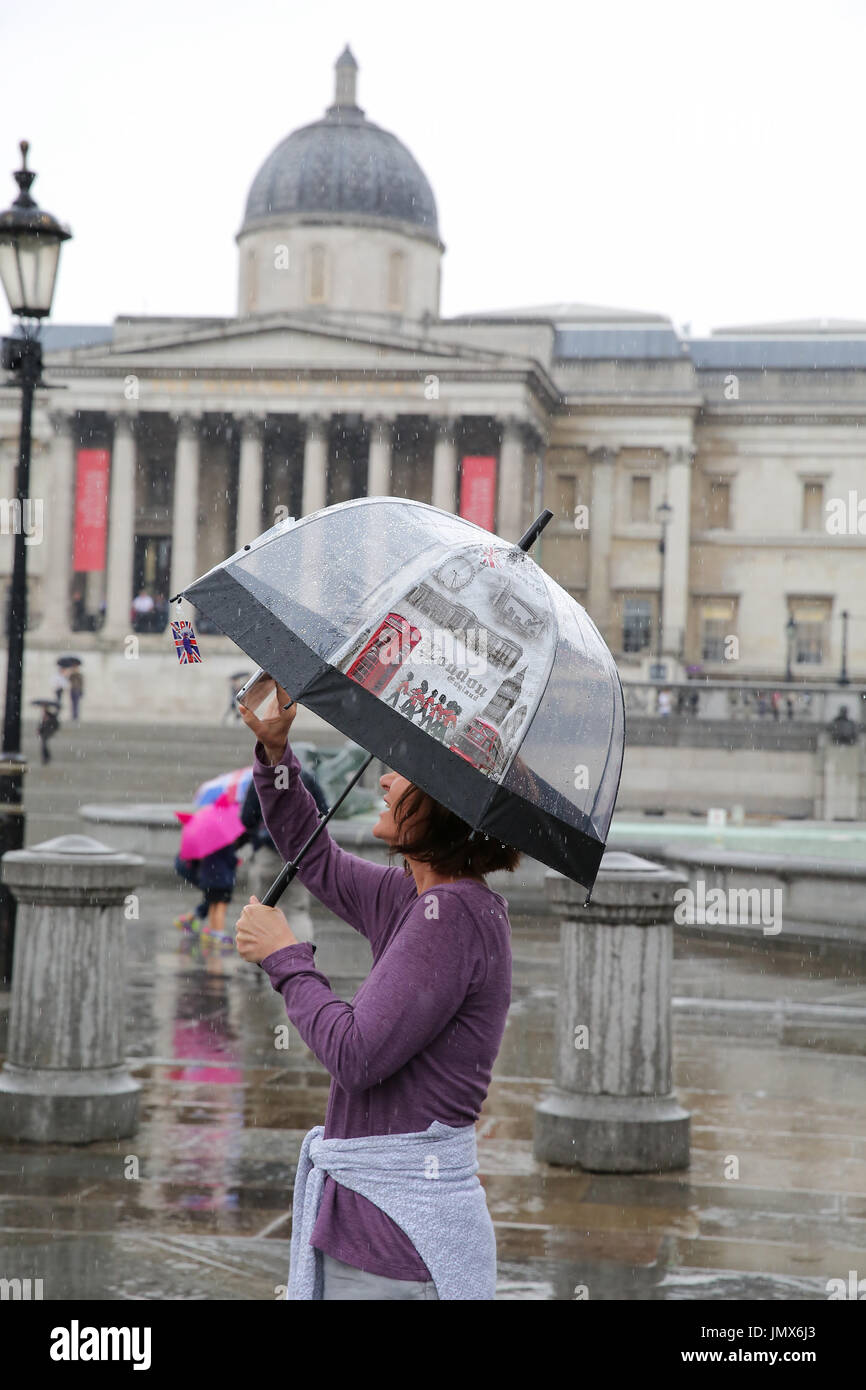 People take shelter from the rain under umbrellas in Westminster after