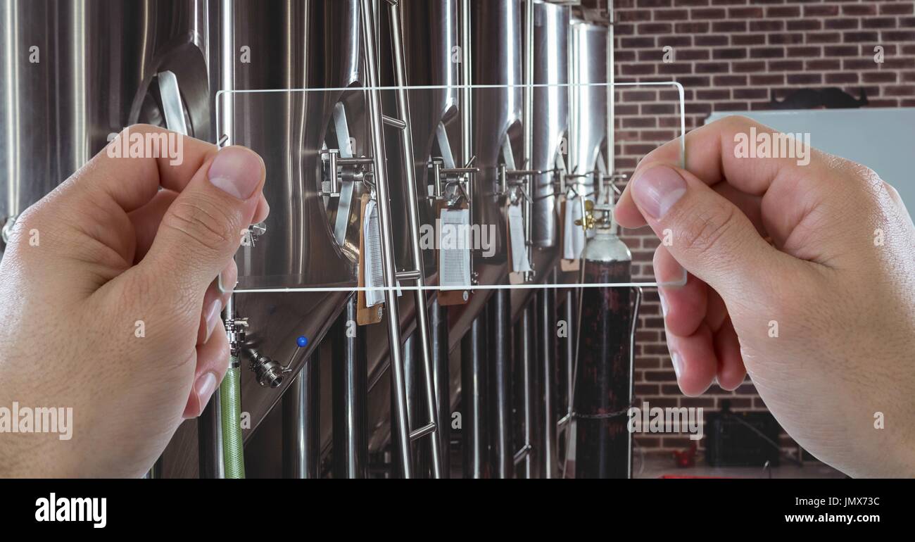 Digital composite of Hands photographing machinery through transparent device at brewery Stock Photo