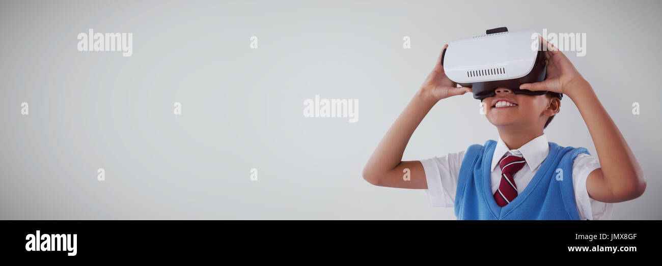 Schoolboy using virtual reality headset against white background Stock Photo