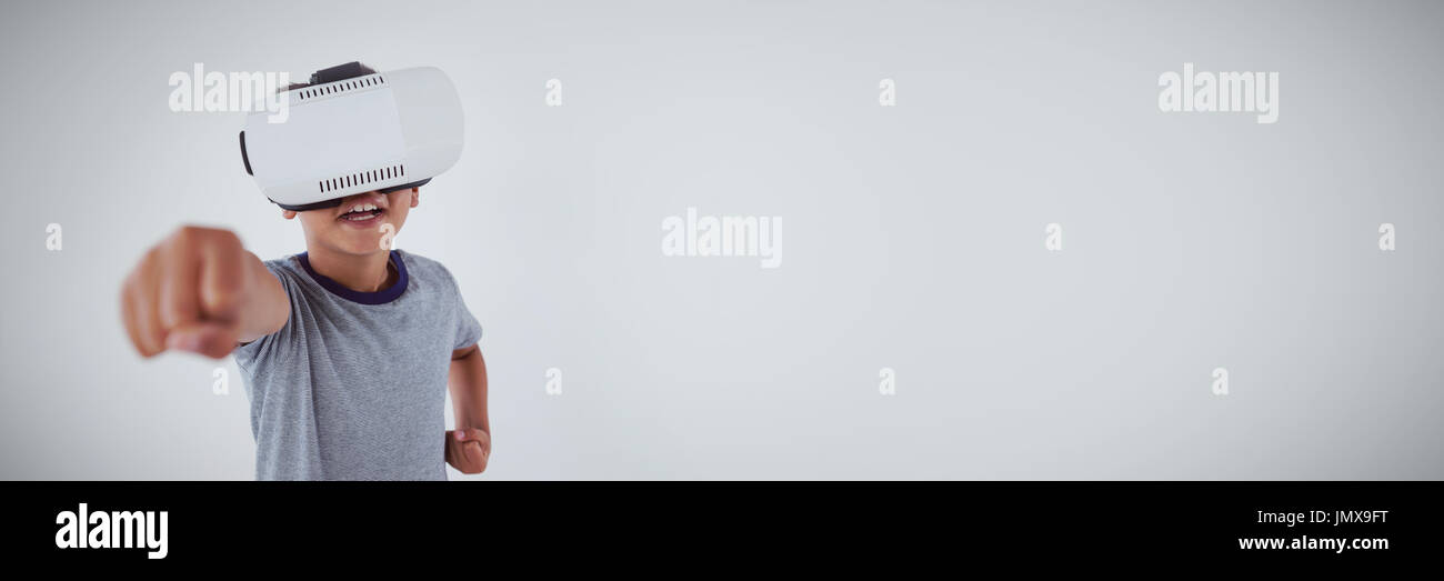 Schoolboy using virtual reality headset against white background Stock Photo