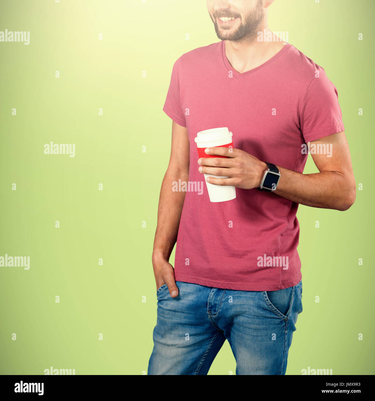 Midsection of smiling model holding disposable coffee cup against green background Stock Photo