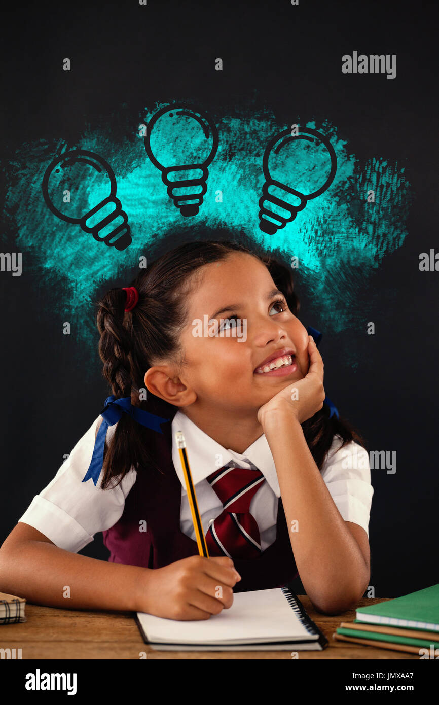 Digital composite image of light bulbs on blue spray paint against schoolgirl doing her homework against chalkboard Stock Photo