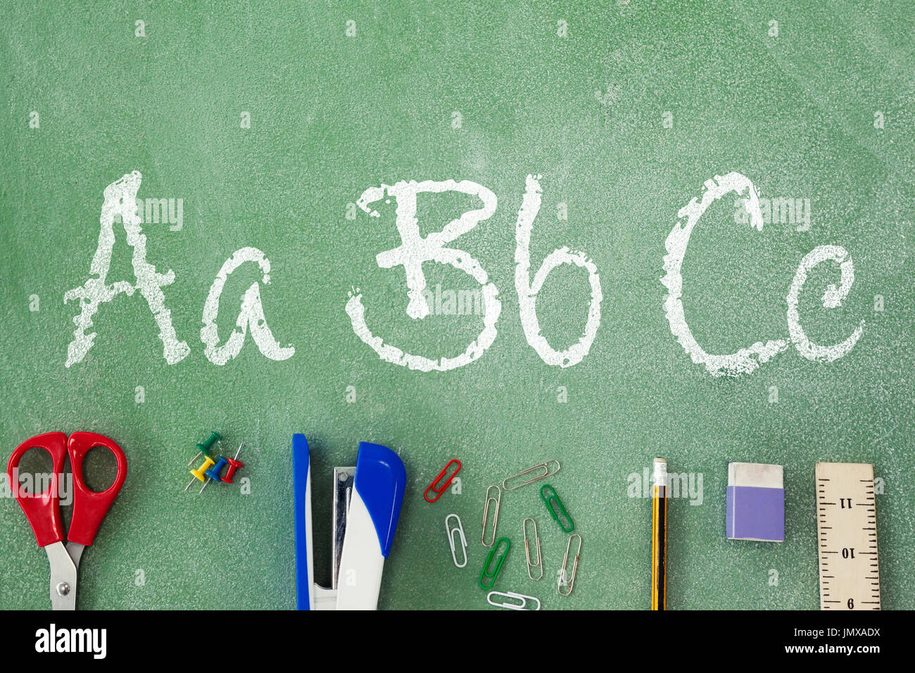 Letters on white background against overhead view of stapler with pencil on table Stock Photo