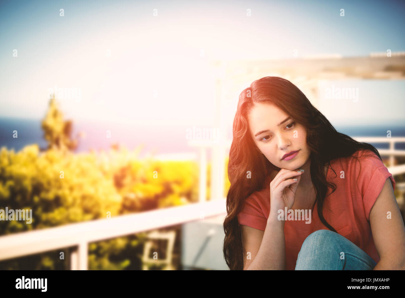 Thoughtful Young Woman Relaxing On Tiled Floor against scenic view of sea against sky Stock Photo