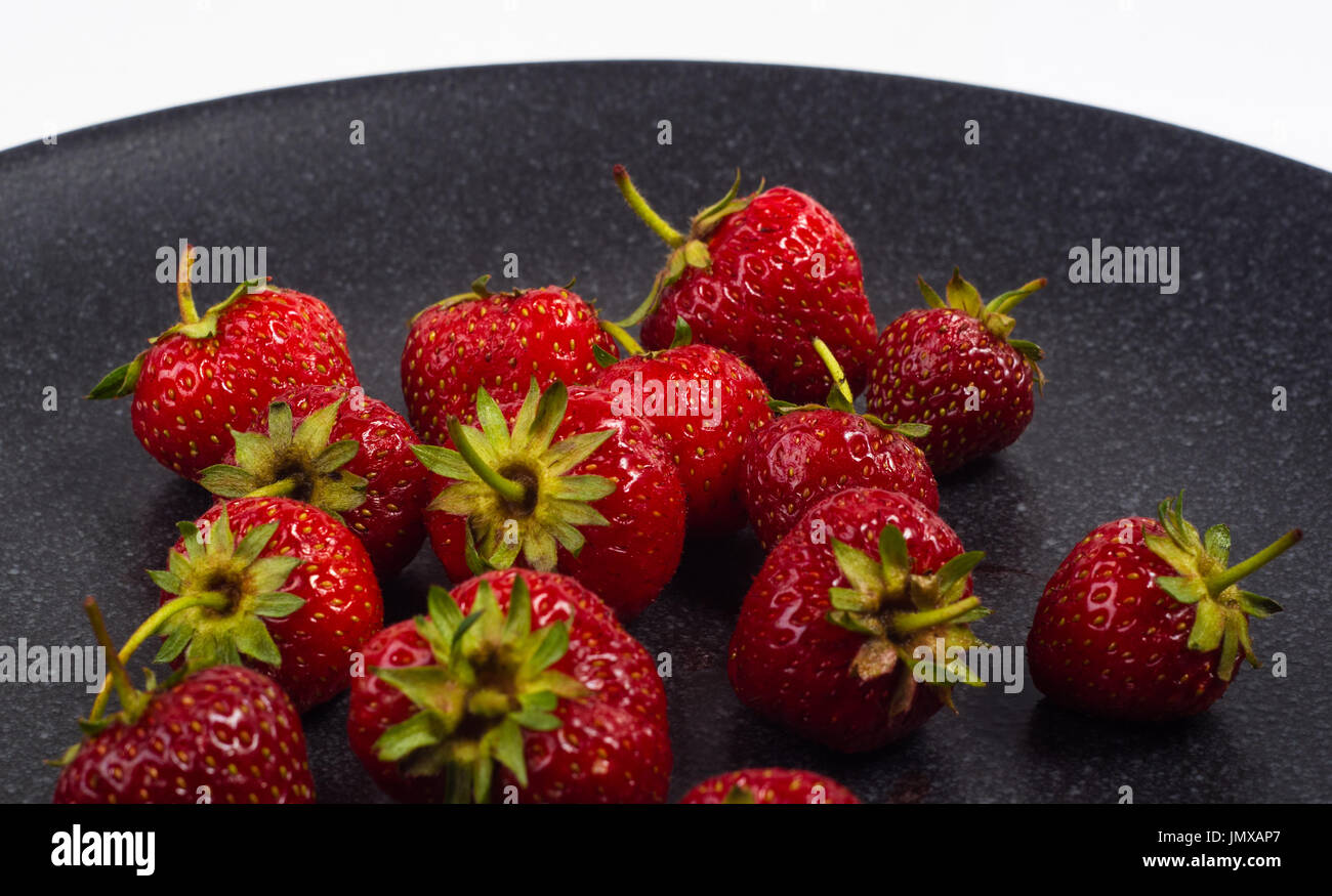 fresh ripe berries strawberries on black ceramic plate on white ...