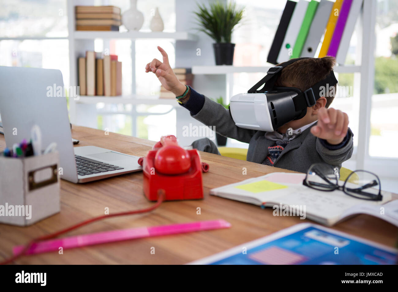 Boy as business executive using virtual reality headset in office Stock Photo