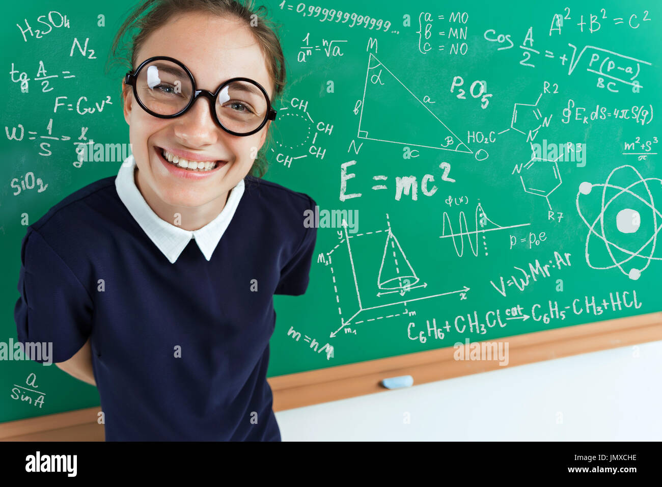 Happy joyful girl near blackboard. Photo of a smart student in uniform. High angle view Stock Photo