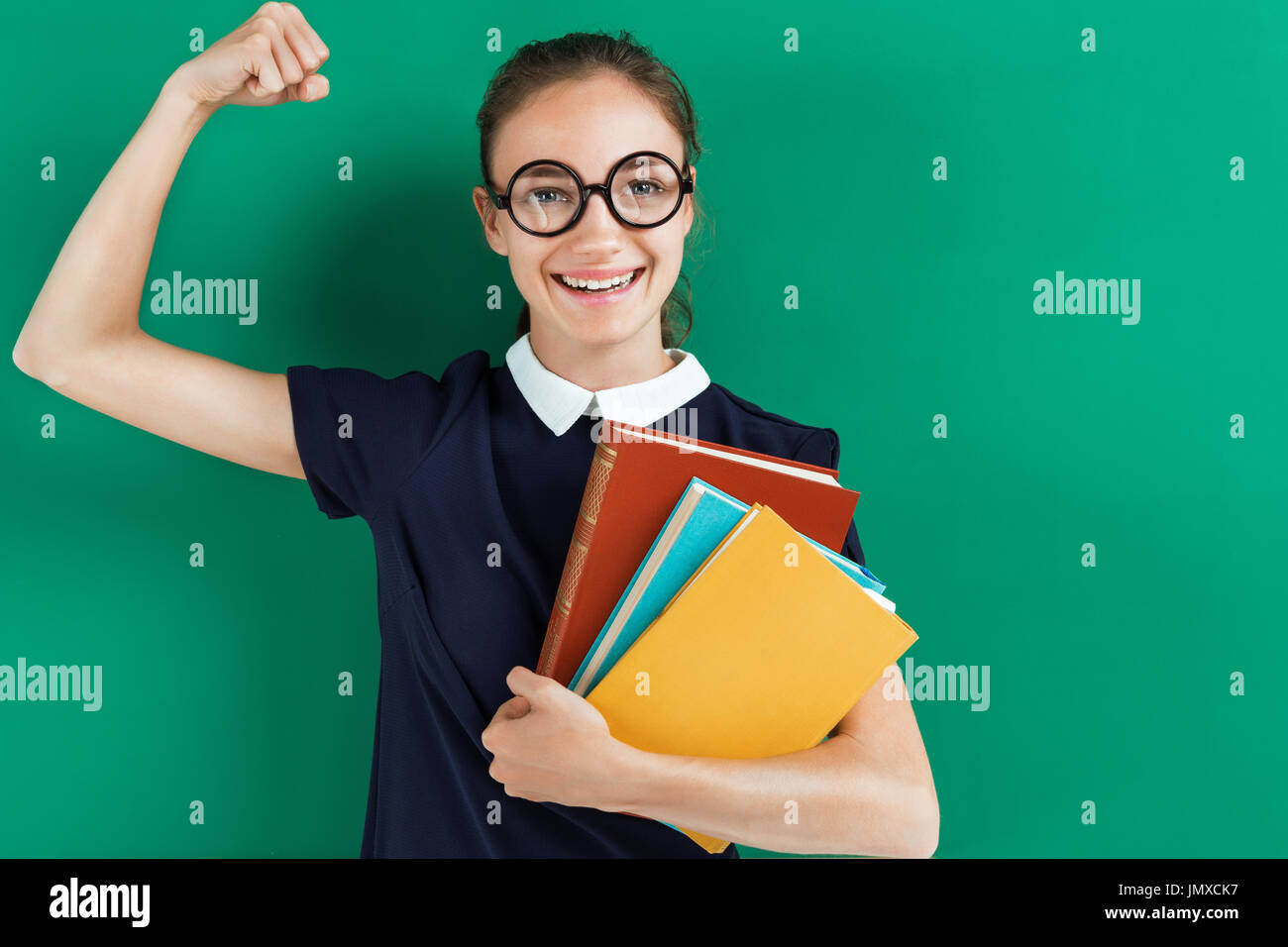 Smiling student hugging books and showing her biceps. Photo of teen ...