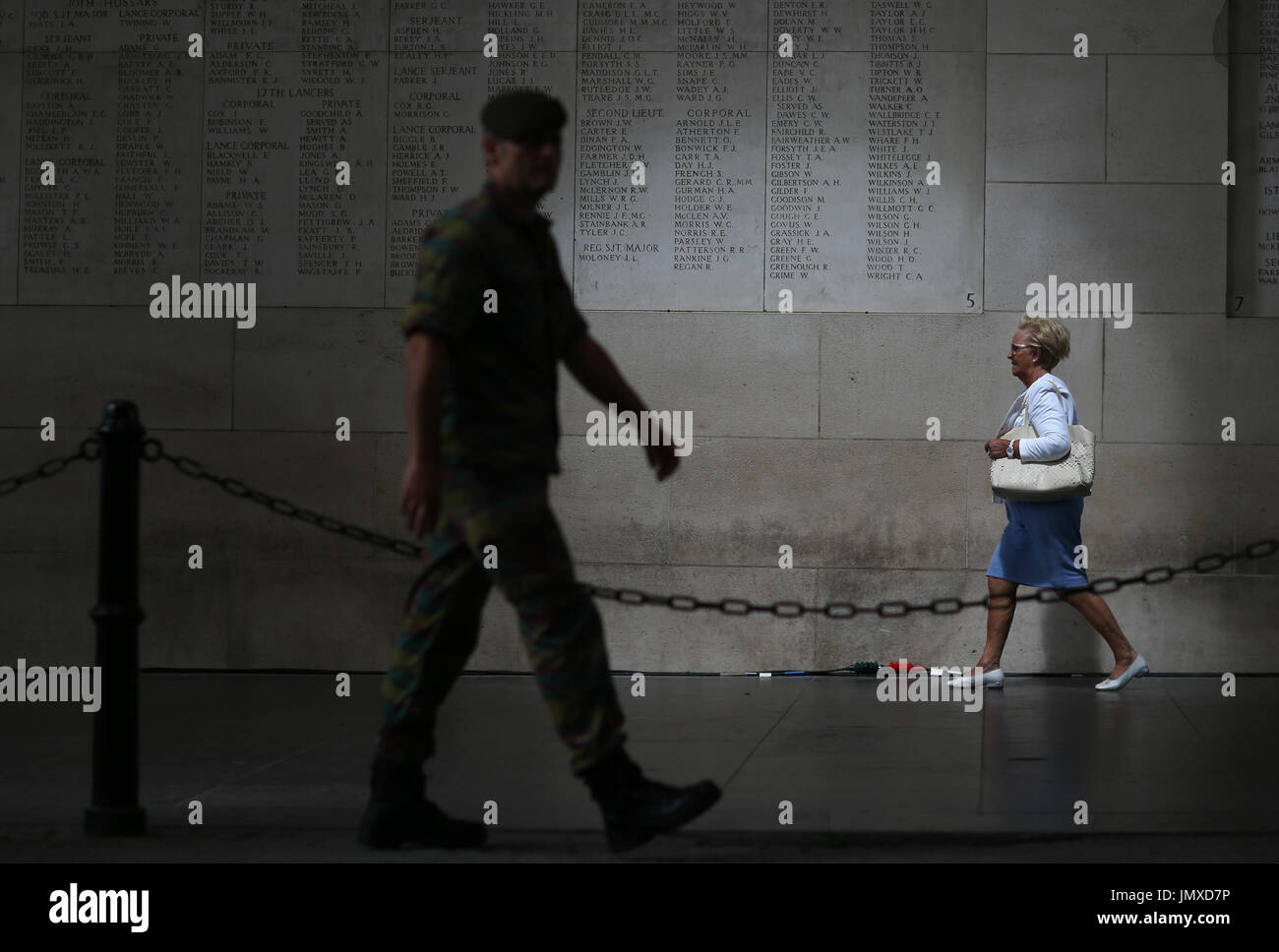 A lady and a soldier walk past a section of the Menin Gate, Ypres, where the names of some of the fallen soldiers are carved ahead of events in Belgium to mark 100 years since the start of the Battle of Passchendaele. Stock Photo