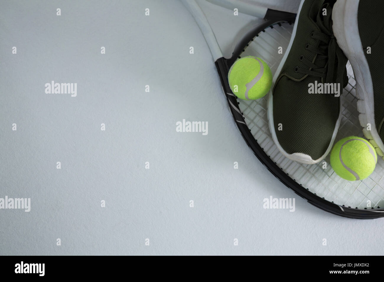Cropped image of sports shoe with balls on racket over white background ...