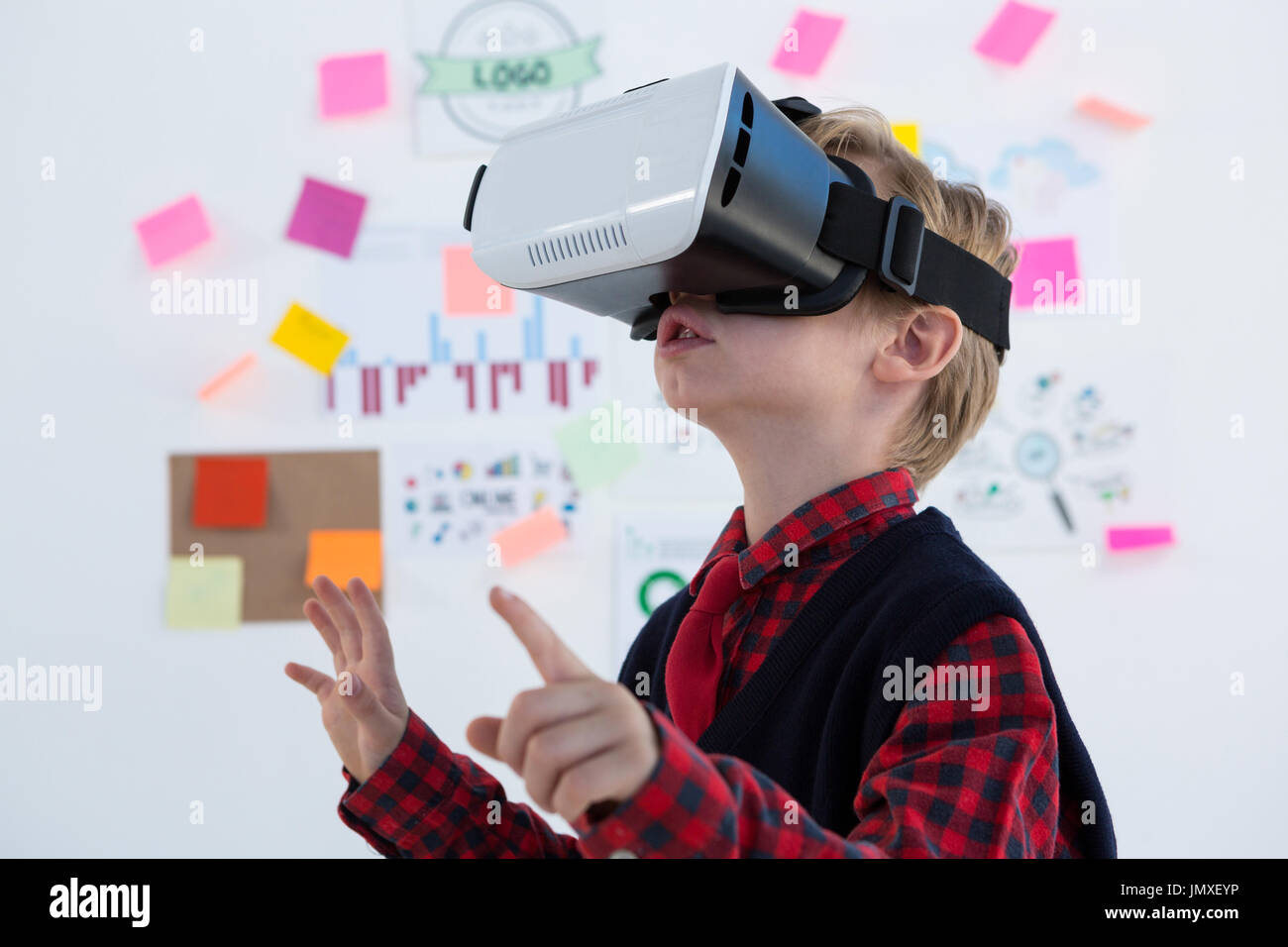Boy as business executive using virtual reality headset in office Stock Photo