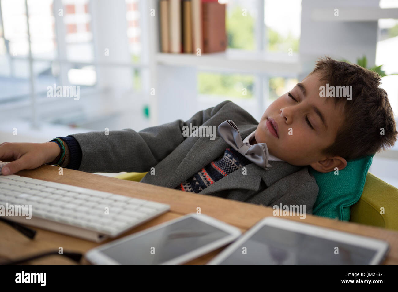 Boy as business executive sleeping in office Stock Photo