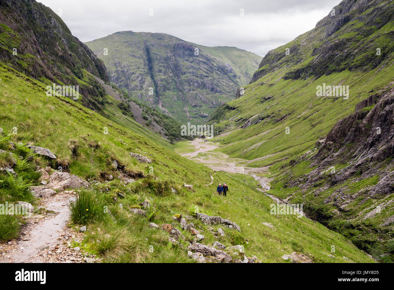 View down the Hidden or Lost Valley (Coire Gabhail) with hikers walking up path from Glen Coe pass. Glencoe, Lachabar, Highland, Scotland, UK Stock Photo