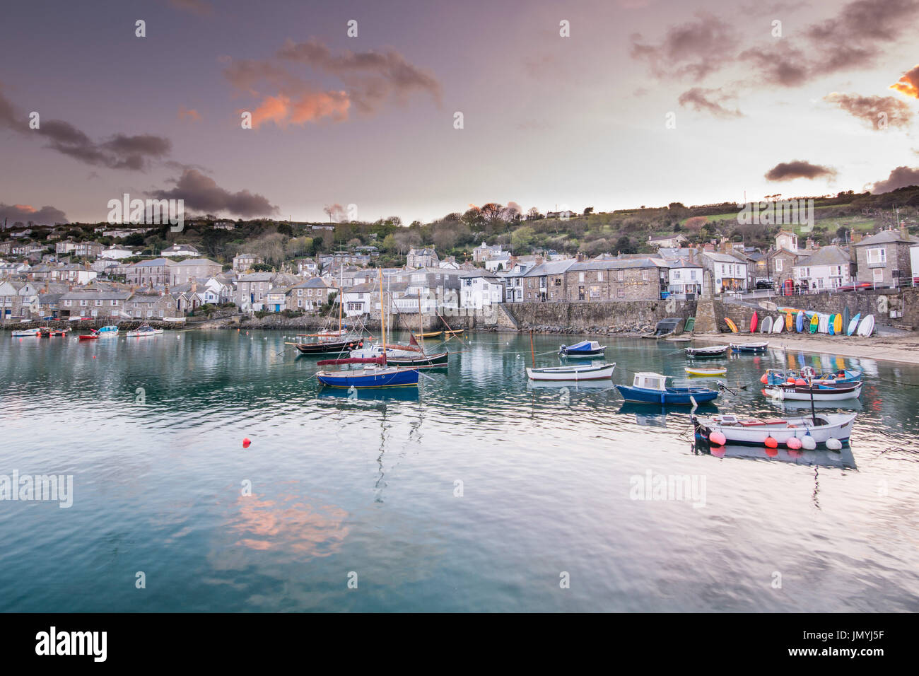 Sunset at Mousehole Harbour with boats and clouds reflecting in the water. Stock Photo