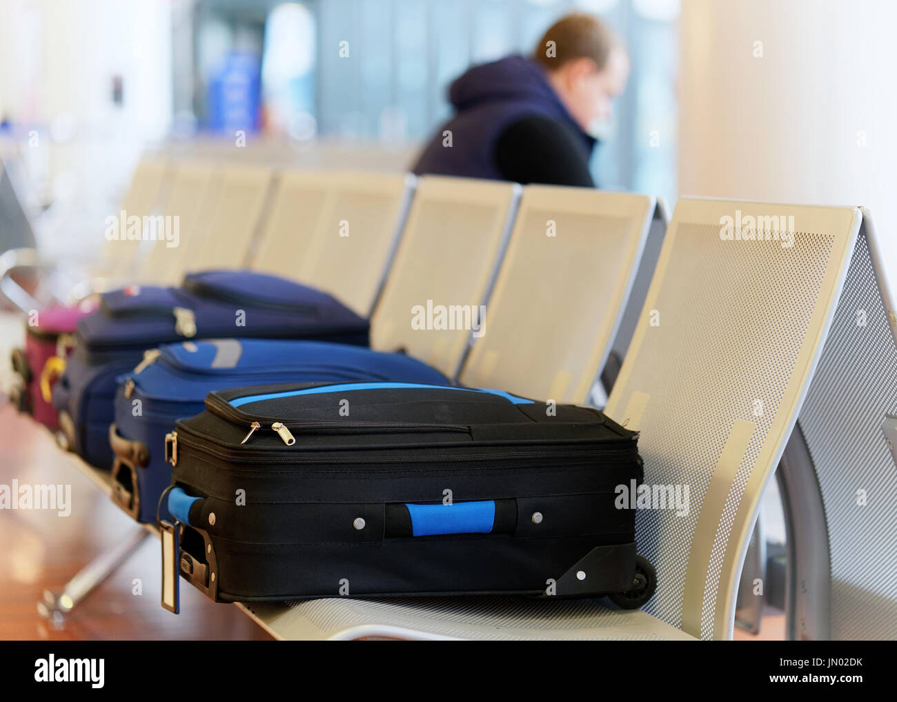 Luggage laying in the chair in the departure hall of Milan-Bergamo airport in Italy. Passenger on the background Stock Photo