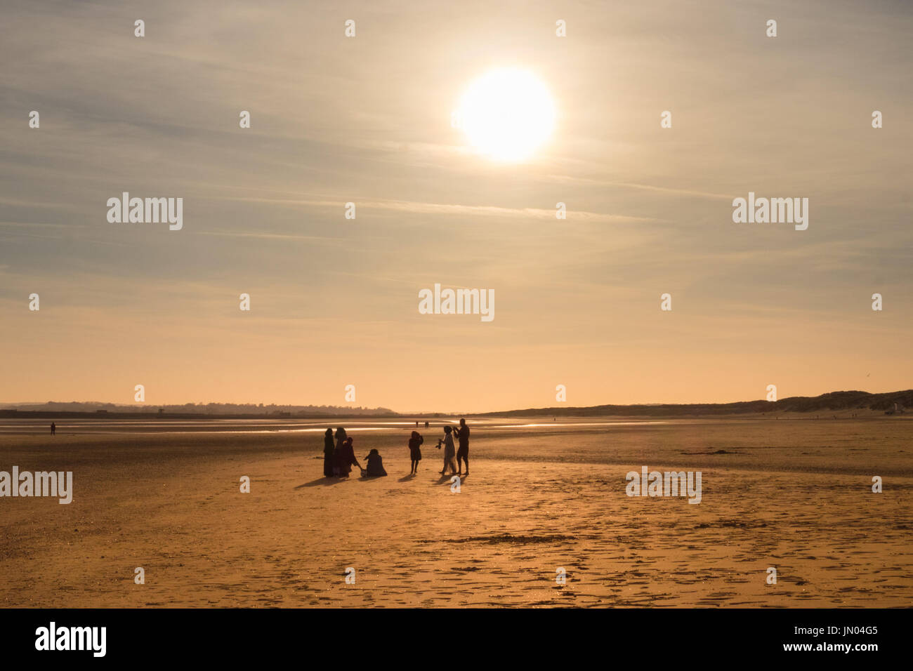 Silhouettes of a family at sunset on Camber Sands Beach at low tide, East Sussex, England Stock Photo