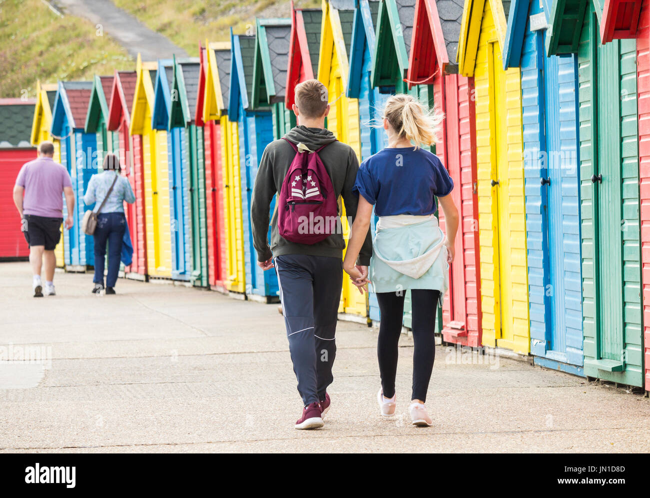 Whitby, North Yorkshire, England, UK. 29th July, 2017. Weather: Morning stroll past beach huts on a glorious morning in Whitby as Steampunks arrive for the Whitby Steampunk weekend. Credit: ALAN DAWSON/Alamy Live News Stock Photo
