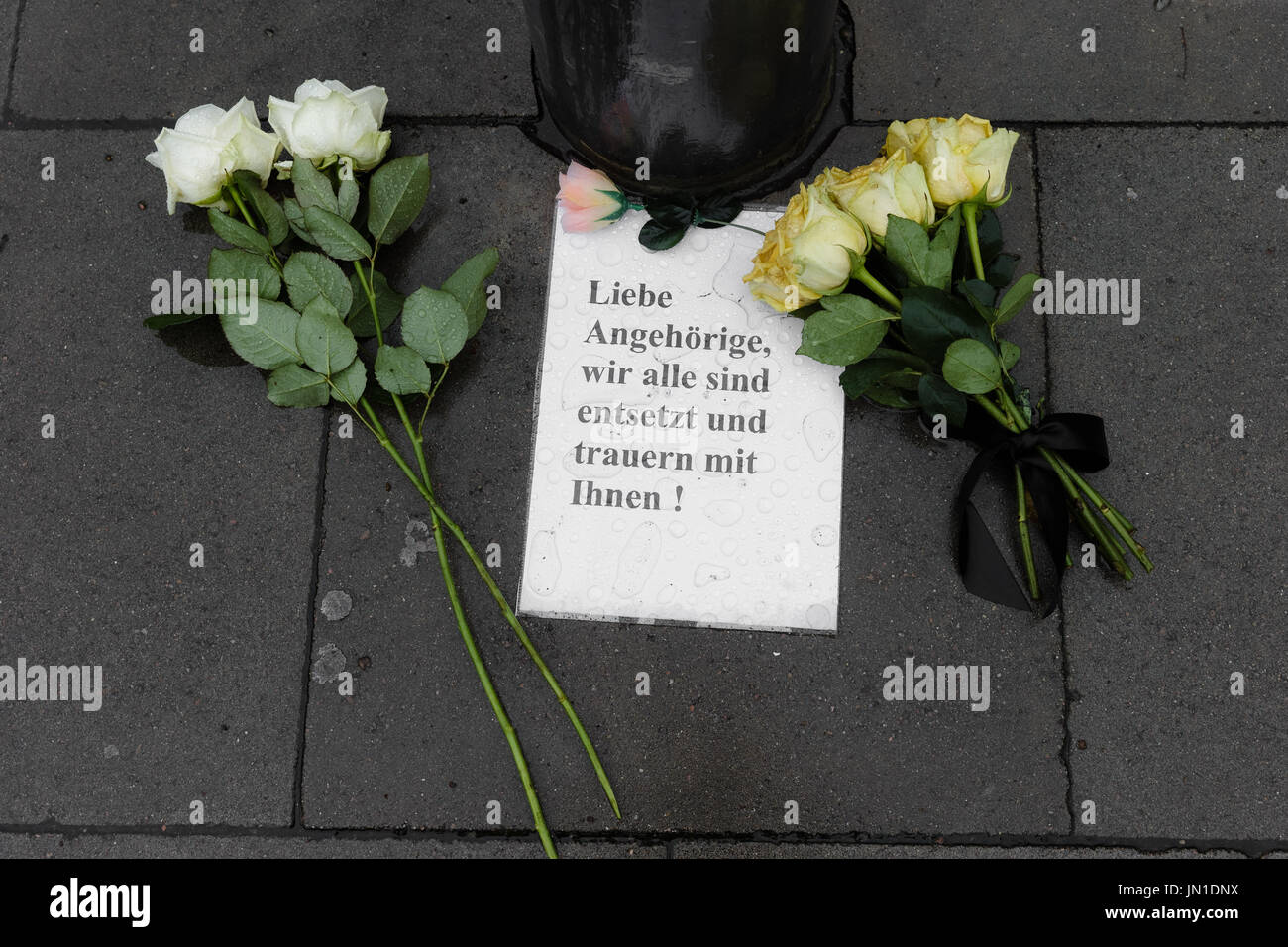 Hamburg, Germany. 29th July, 2017. Roses and an opened letter saying 'Liebe Angehoerige, wir alle sind entsetzt und trauern mit Ihnen!' (lit. Dear relatives: we all are shocked and mourn with you!) lie on the pavement in front of the supermarket where a man killed another person and injured six furhter people in Hamburg, Germany, 29 July 2017. Photo: Markus Scholz/dpa/Alamy Live News Stock Photo