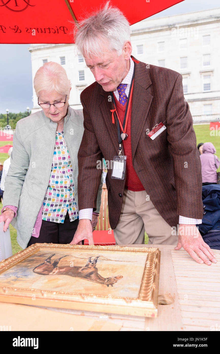 Belfast, Northern Ireland.  29/07/2017 - Paintings expert Michael Welch examines a painting of a race horse as the Antiques Roadshow comes to Stormont Estate. Stock Photo