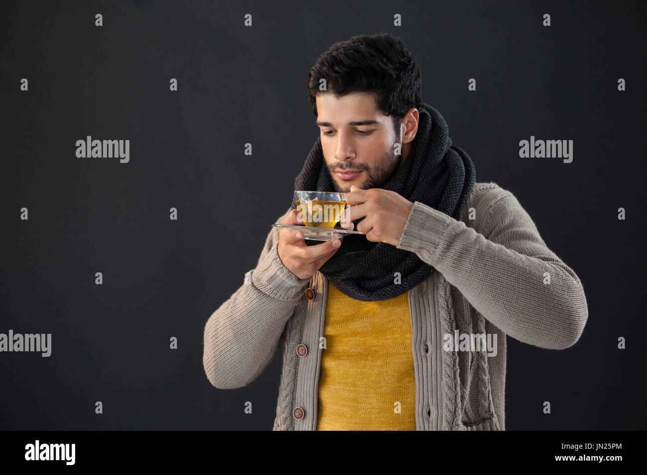 Man having a cup of lemon tea against black background Stock Photo - Alamy