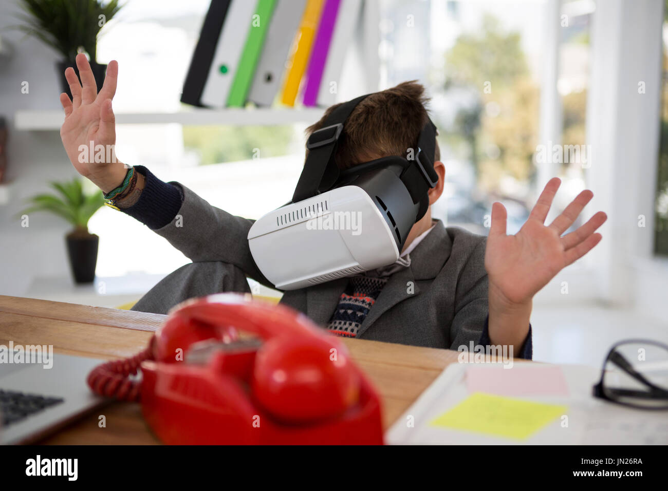 Boy as business executive using virtual reality headset in office Stock Photo
