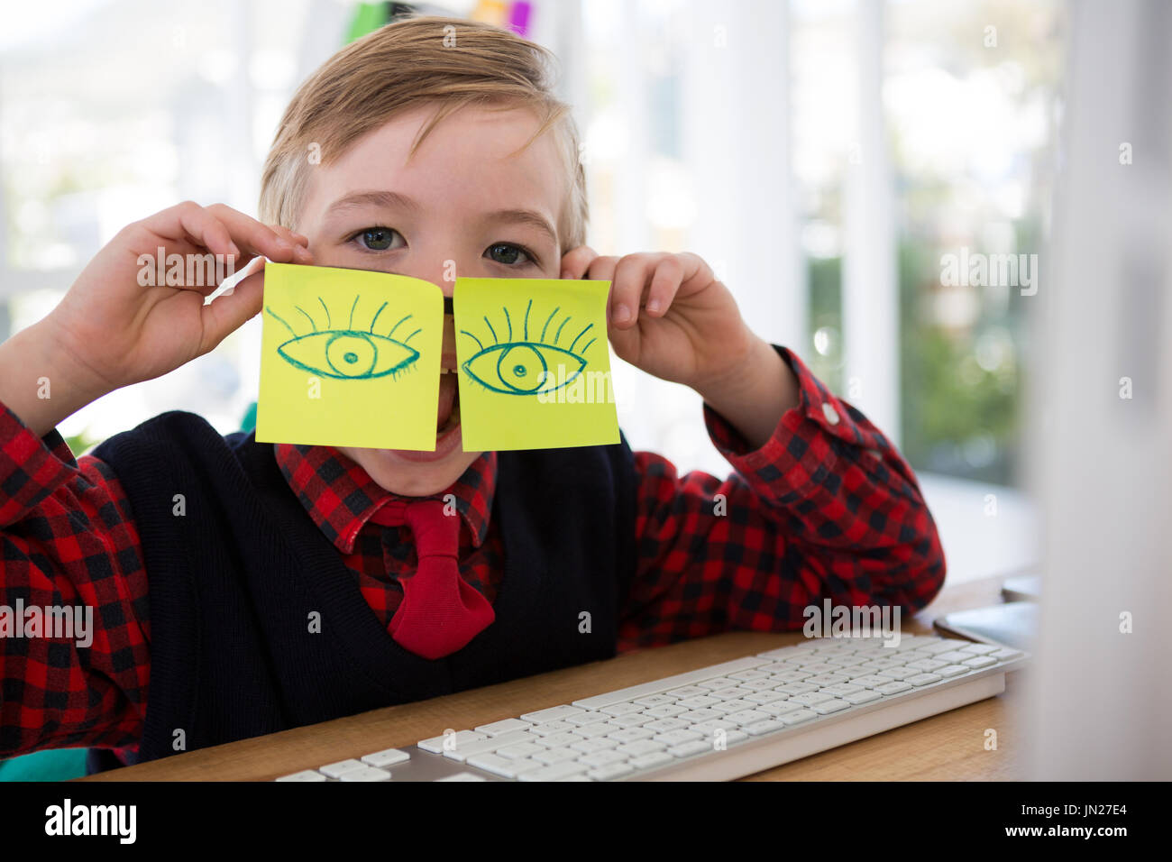 Boy as business executive with sticky notes on his face in office Stock Photo