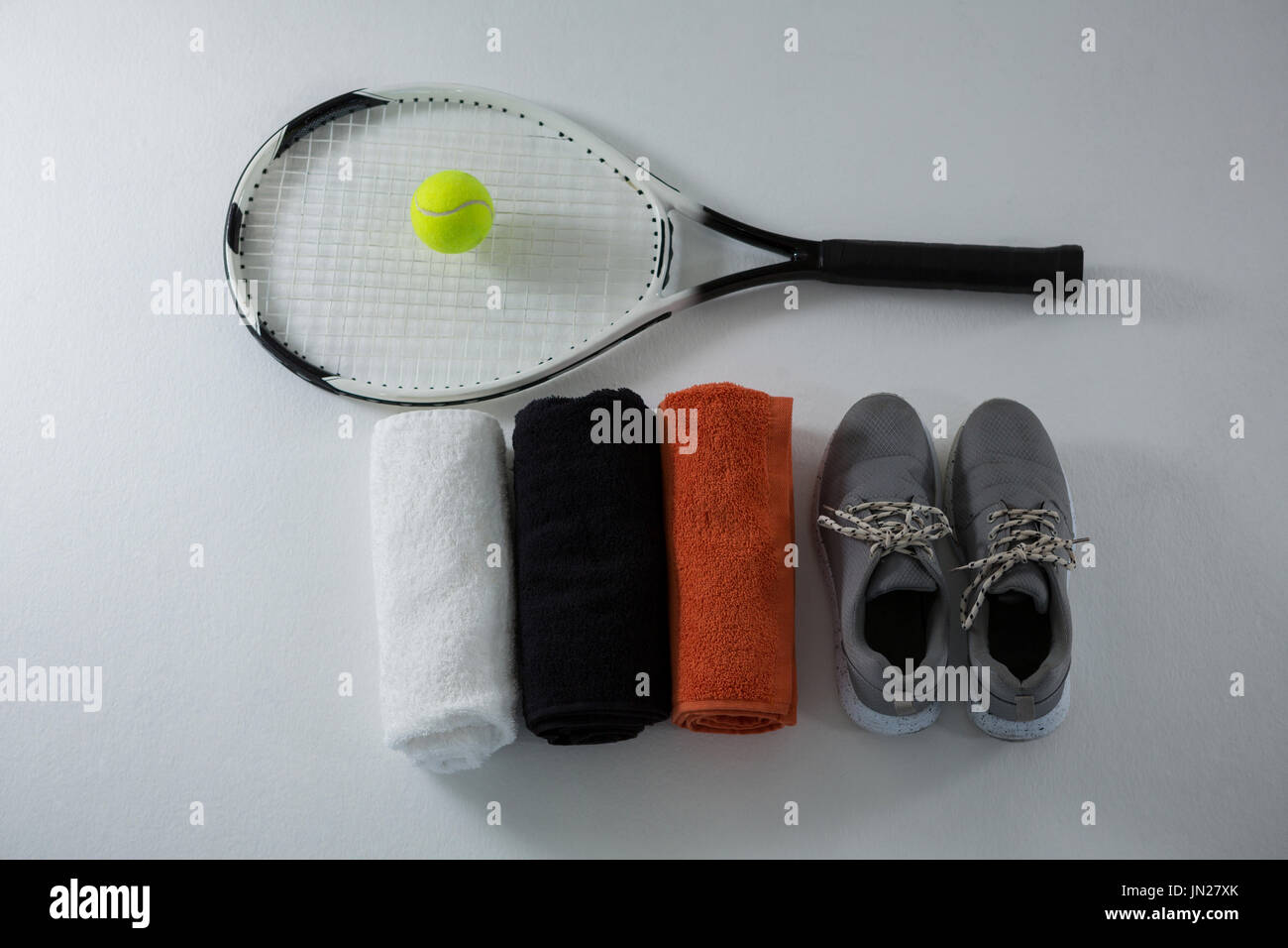 Overhead view of ball on racket by napkins and sports shoe over white ...