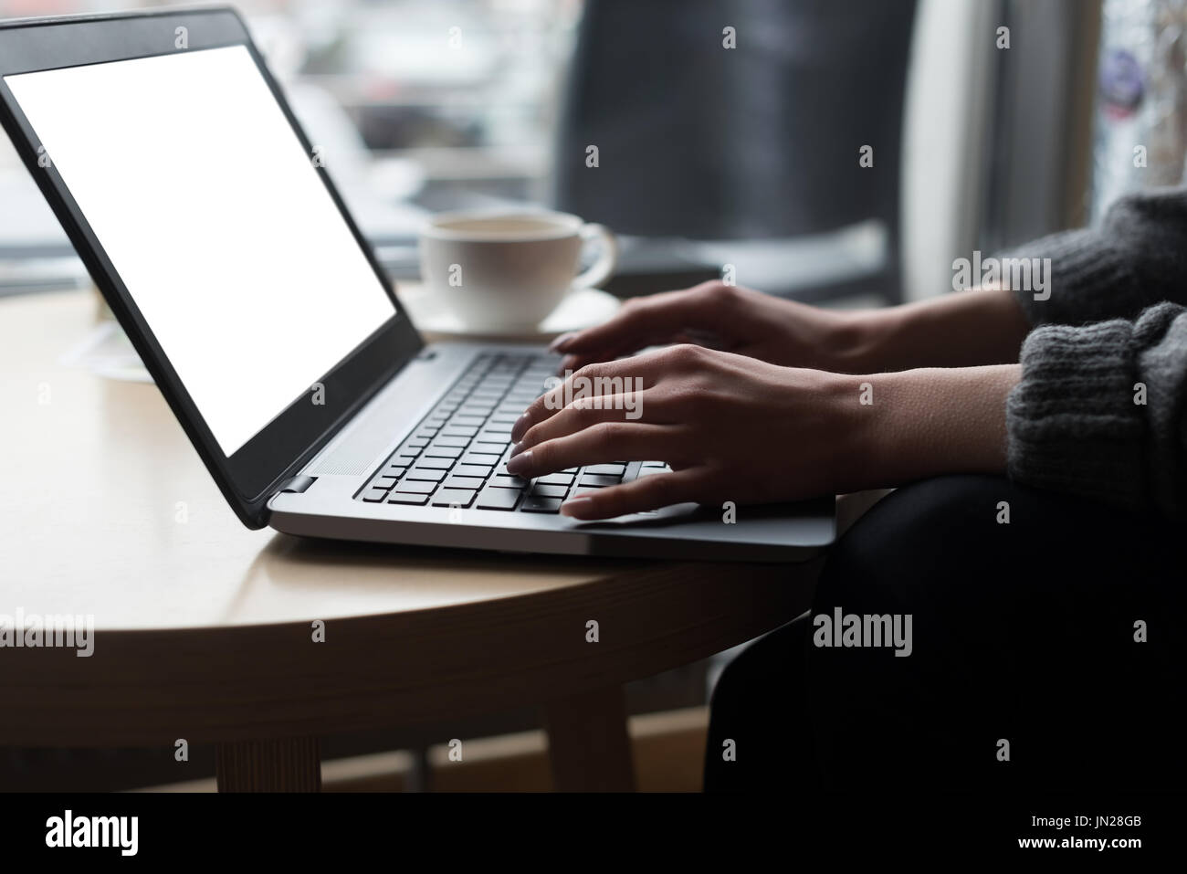 Cropped image of woman using laptop at table in cafe Stock Photo