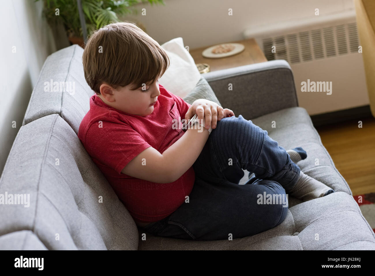 High angle view of boy using smart watch while sitting on sofa at home Stock Photo