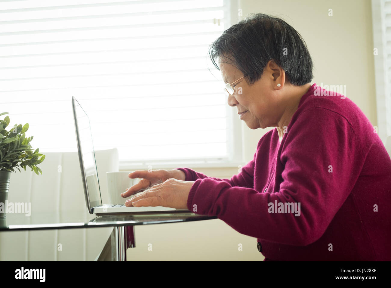 Side view of senior woman using laptop while sitting at table Stock Photo