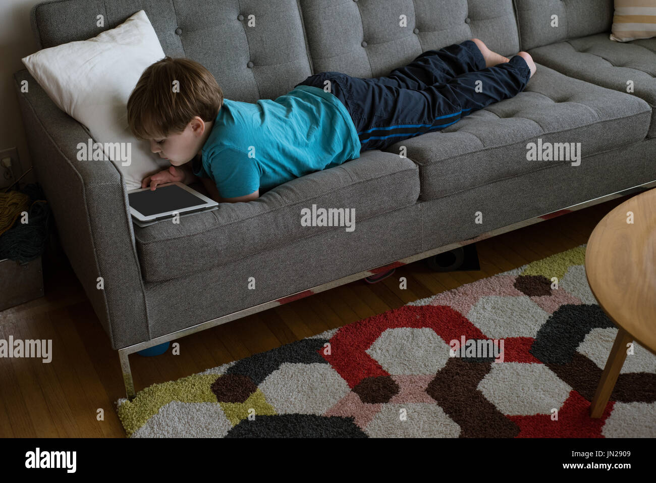 High angle view of boy using digital tablet while lying on sofa at home Stock Photo