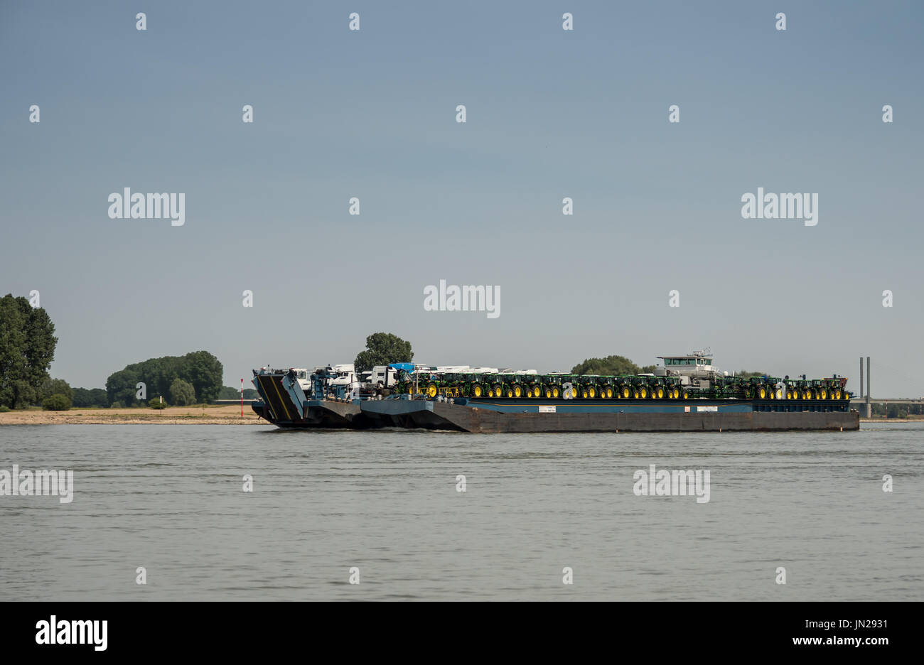 Transport ship loaded with tractors and trucks driving downstream the ...