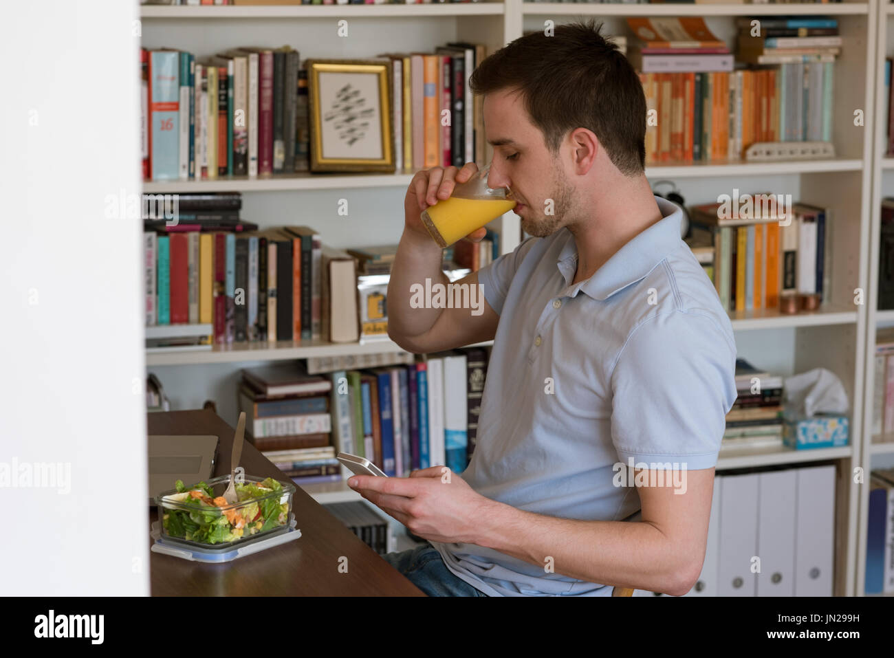 Man having juice while using mobile phone at table Stock Photo