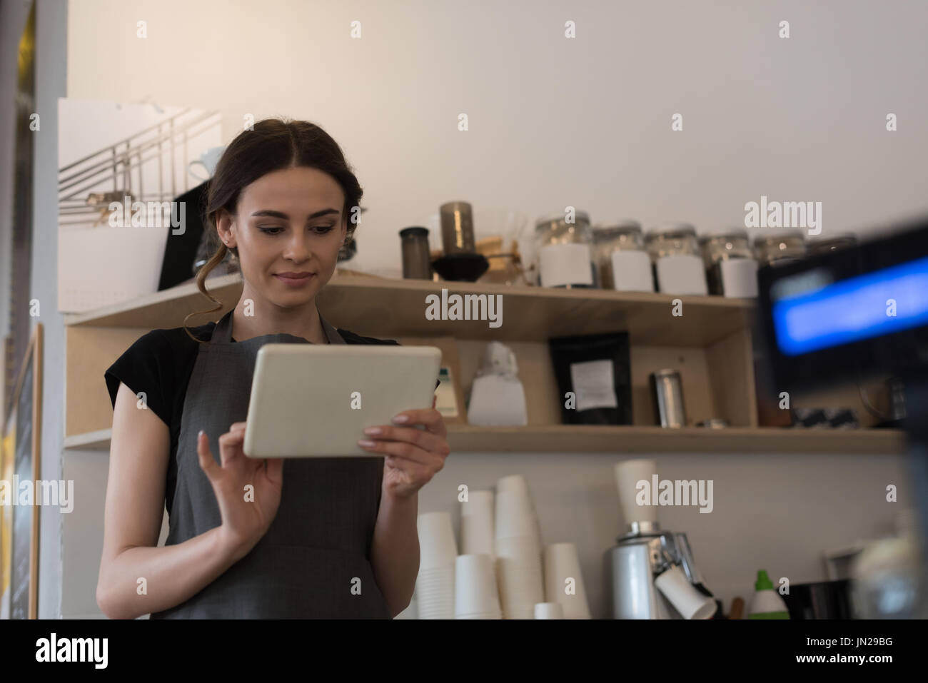 Female owner using digital tablet while standing in kitchen at cafe Stock Photo