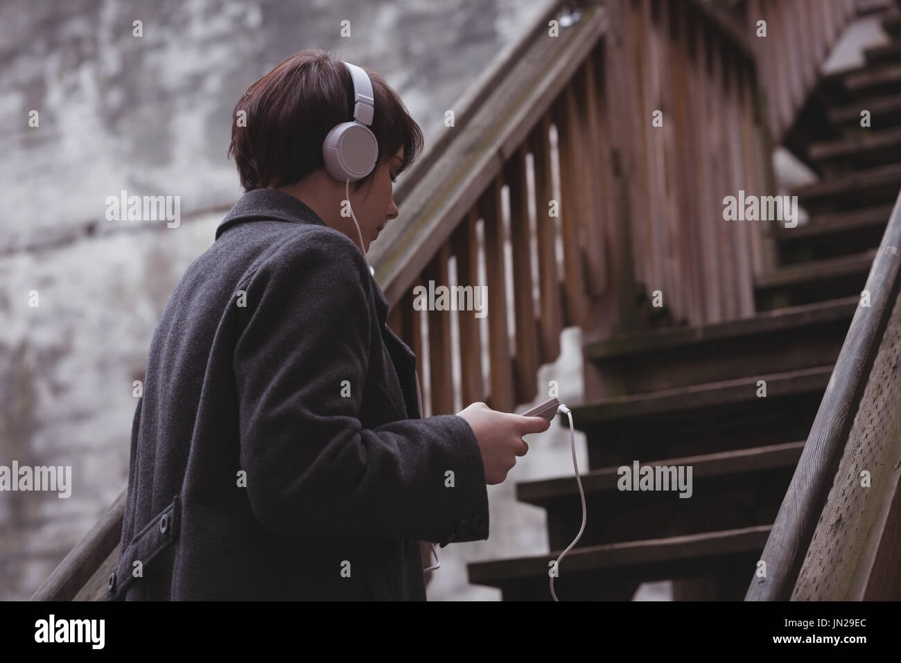 Woman listening to music on headphones while climbing up the stairs