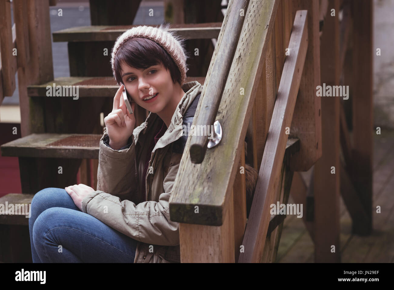 Woman talking on mobile phone while sitting on stairs Stock Photo