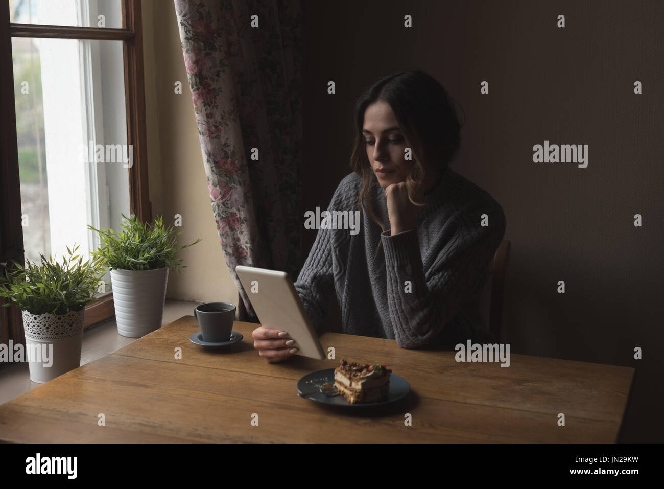 Woman using tablet computer while by window at home Stock Photo