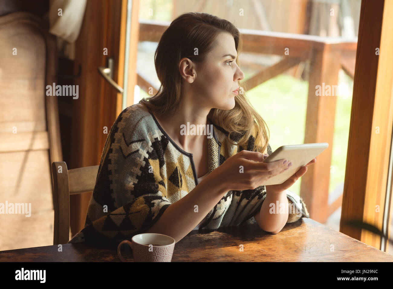 Thoughtful woman using digital tablet at home Stock Photo