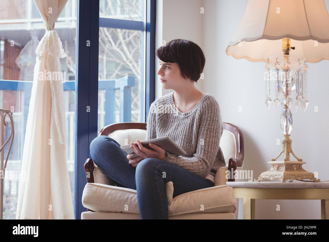 Thoughtful woman using digital tablet at home Stock Photo